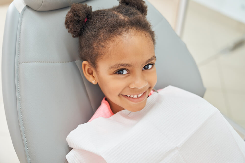 little girl sitting in dental chair smiling