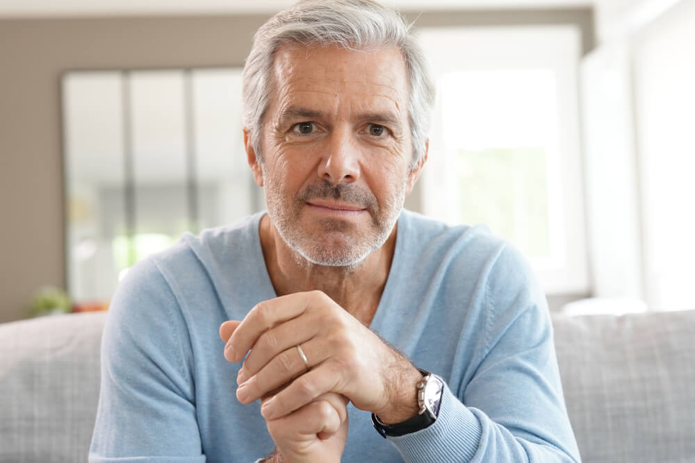 attractive senior man with blue sweater relaxing at home