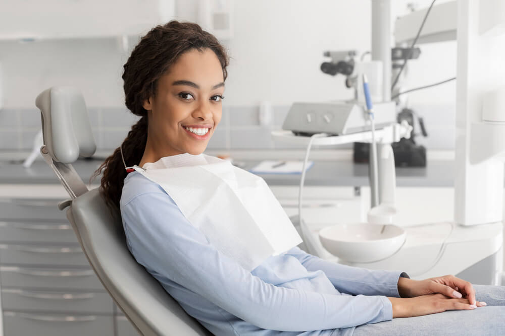 Young lady sitting in dentist chair and smiling at camera