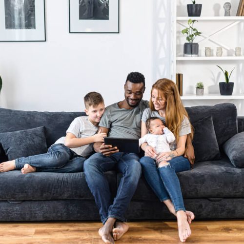family relaxing with a digital tablet sitting on the comfortable sofa